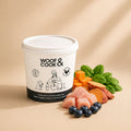 Container labeled 'Woof & Cook' with raw pet food ingredients on a beige background